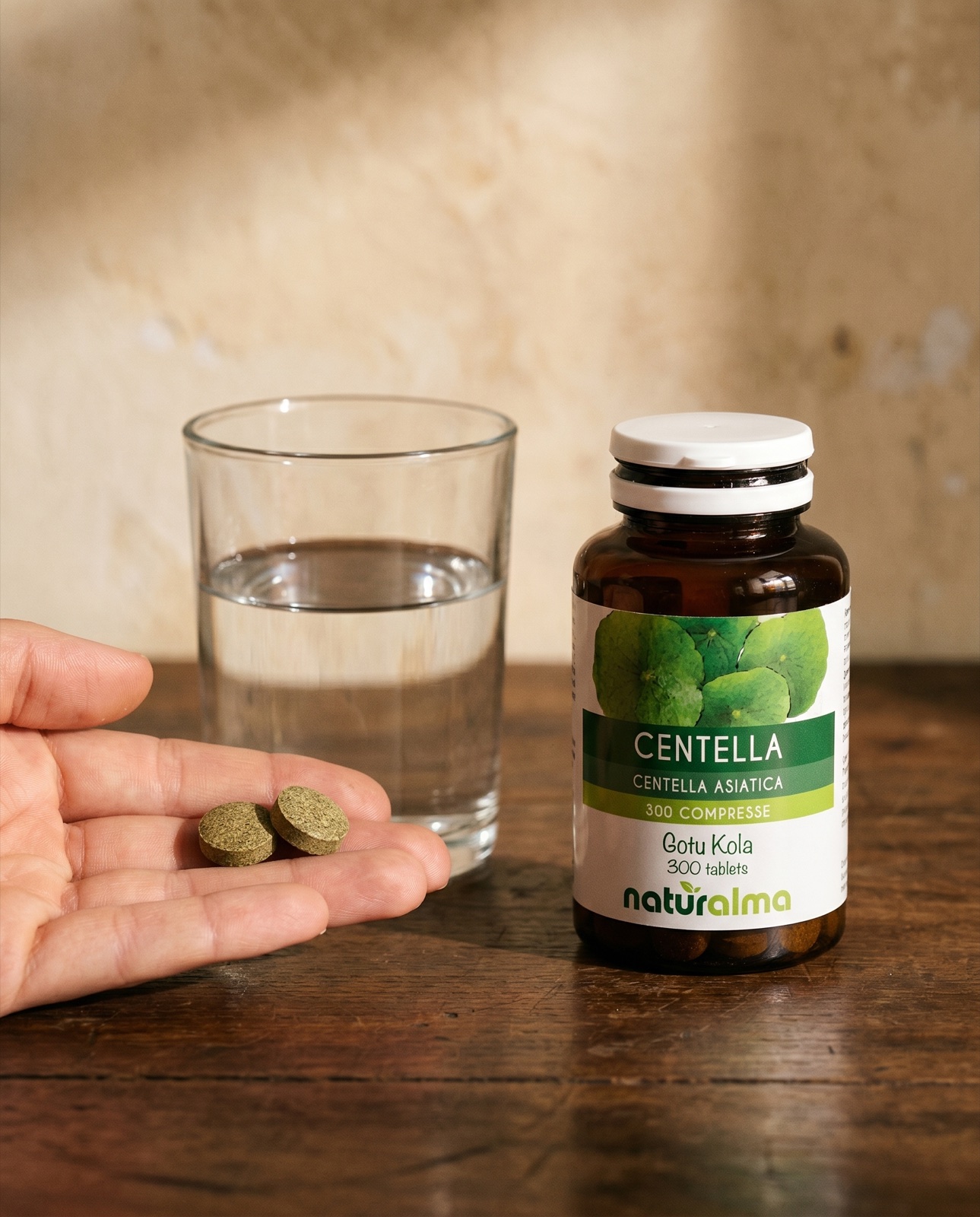 Centella asiatica — a hand holding two tablets, a glass of water and the Naturalma jar